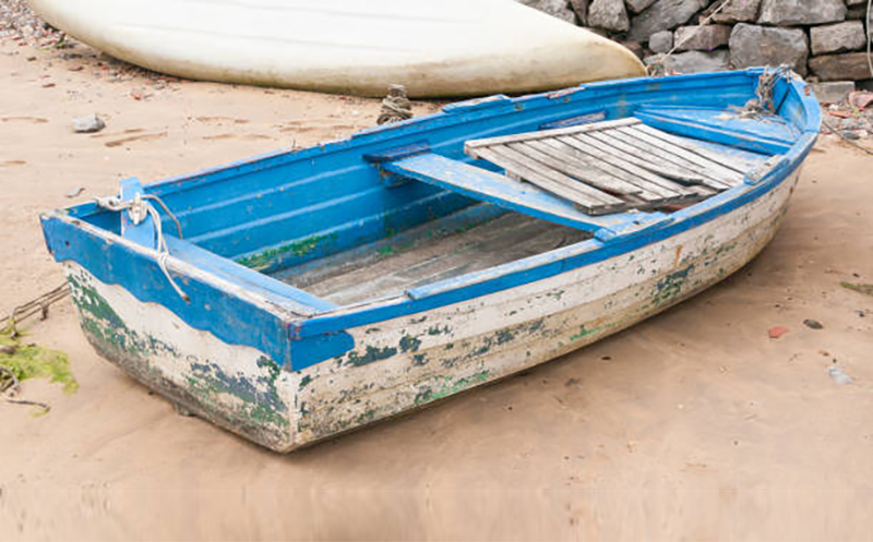 Weathered white and blue wooden boat in a sand beach